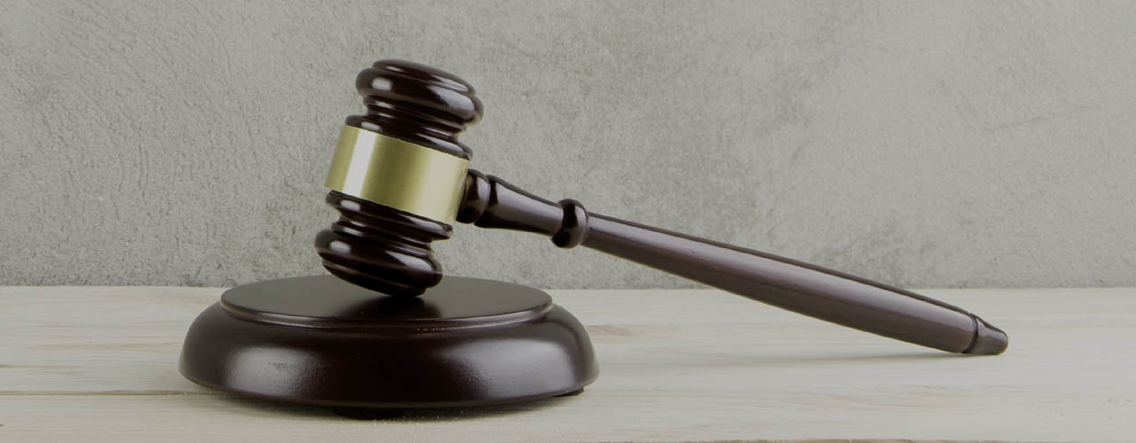 brown gavel with a brass band on a grey background