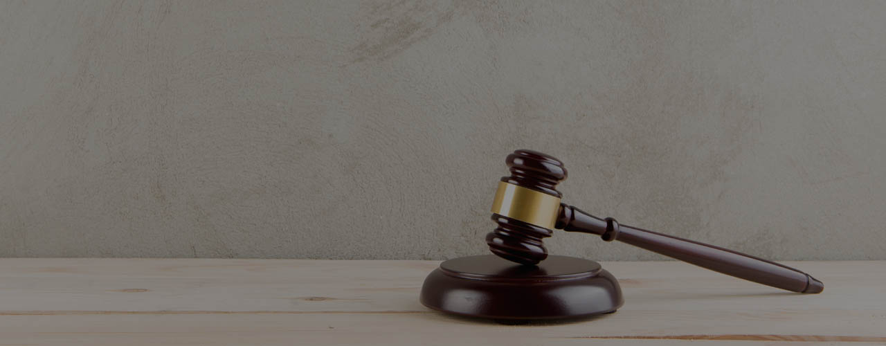 brown gavel with a brass band on a grey background